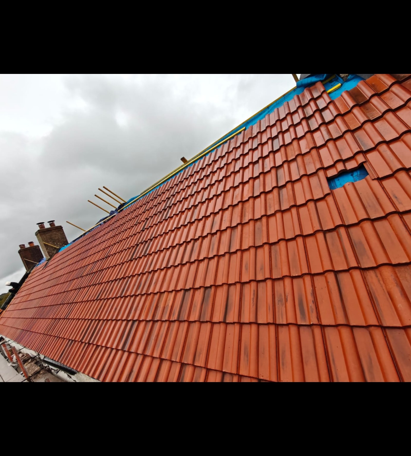 Red roof tiles being installed on the Bristol roofing project