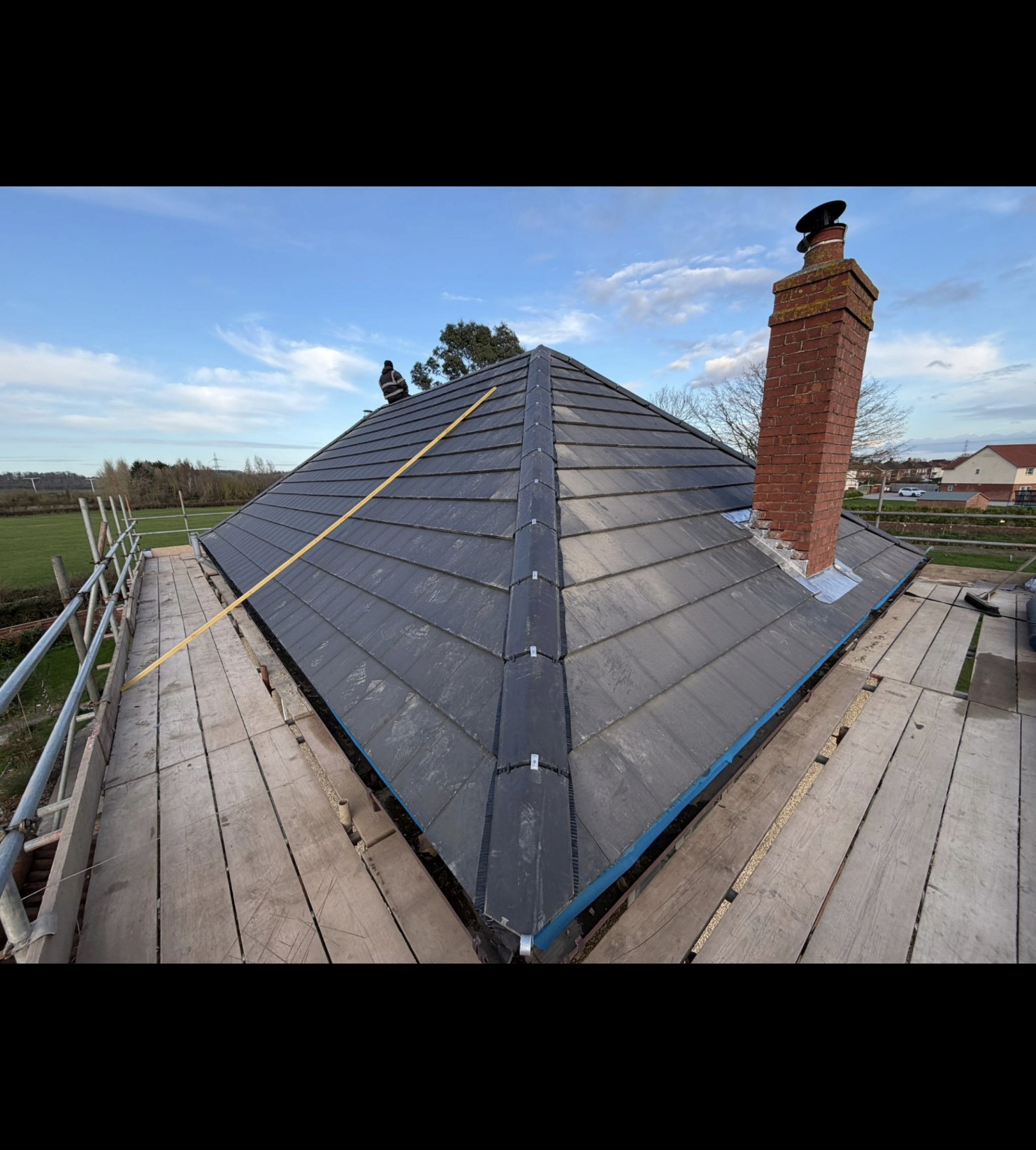 Grey tiled hip roof with chimney flashing on an Ominiworks roofing project in Bridgwater
